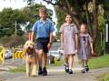 Roman Velovski, Angelique Alifierakis and Aria Marocchini walk with their school's well-being dog ahead of national Walk Safely To School Day. Picture by Chris Lane